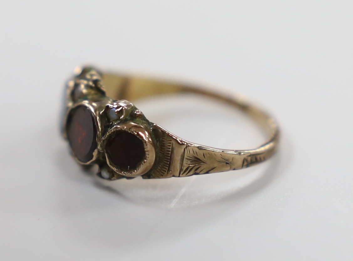 A 19th century yellow metal and graduated four stone foil backed garnet set half hoop ring, with seed pearl spacers, size L, gross weight 1.8 grams, (shank a.f.)